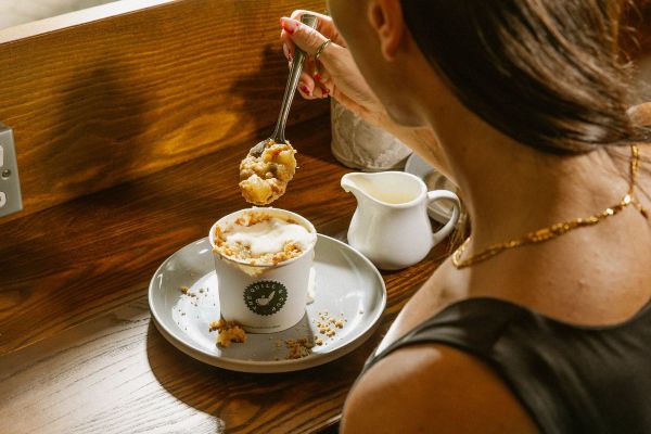 A crumble pot filled with fresh custard. A lady has take a big spoon full